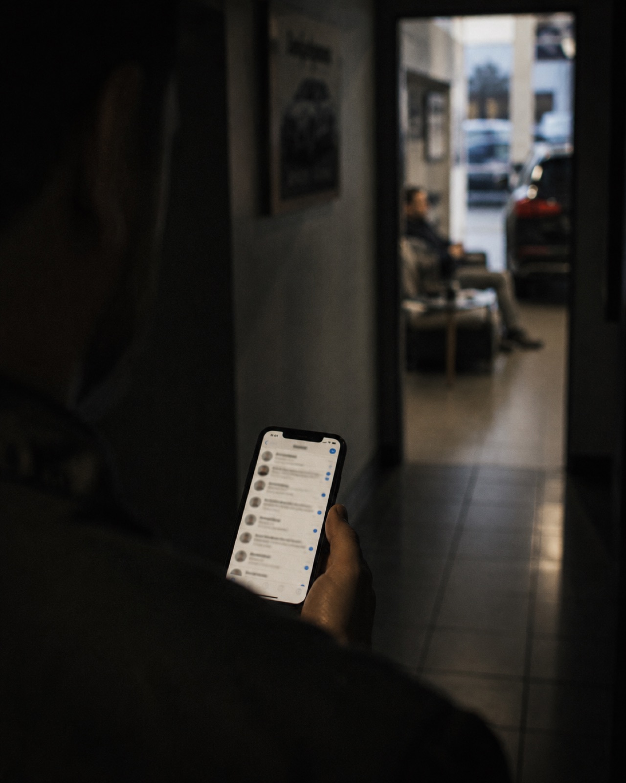 A salesperson checks a long message thread while a customer waits in the distance